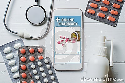 Online pharmacy. Application in smartphone for online ordering of medicines. Lots of pills, stethoscope and spray with medication Stock Photo