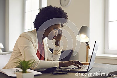 Thoughtful confused young african american businesswoman looking at laptop Stock Photo