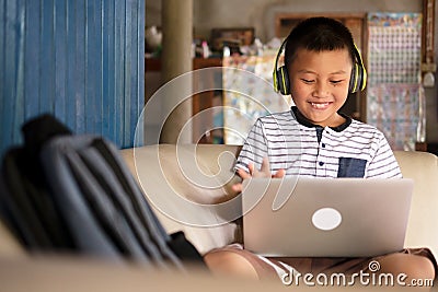 Online remote learning, distance education and homeschooling concepts. School kid Asian preteen boy in headphone using laptop Stock Photo