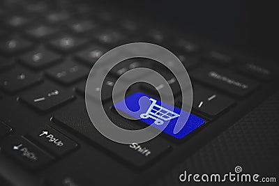 Online shoping concept. Shoping cart on blue laptop keyboard Stock Photo