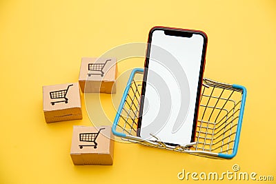 Online shopping concept. Boxes, basket and smartphone isolated on yellow background Editorial Stock Photo