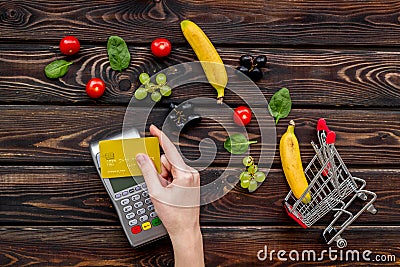Online shopping concept with trolley, credit card, machine for payment near producs on wooden background top view Stock Photo