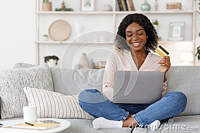 Online Shopping. Positive Black Girl Using Laptop and Credit Card At Home Stock Photo