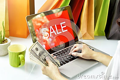 Online shopping, Shopaholic woman holding money cash, Sale promotion sign on laptop computer. Stock Photo