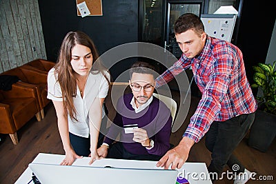 Three businessmen watch internet monitor screen hold credit card Stock Photo