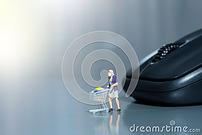 Online shopping. Women with cart in front of black mouse. Miniature people figurines toys conceptual photography Stock Photo