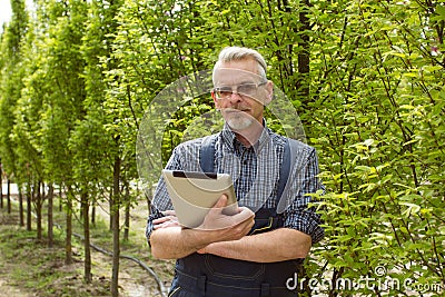 Online Store Manager with a clipboard in hands on a background of a greenhouse Stock Photo