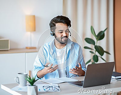 Online Tutoring. Young arab tutor in headset having video call with students Stock Photo