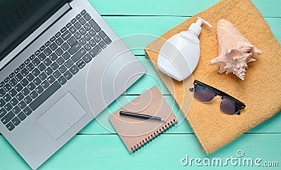 Online work at a beach resort. Laptop, towel, notepad, sunglasses, shell, sunblock, top view, flat lay. Stock Photo