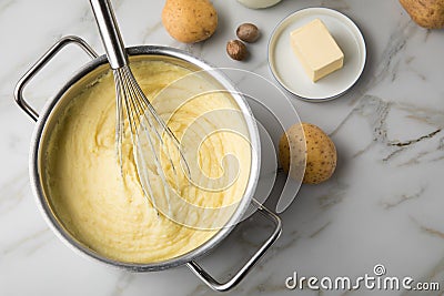 Ooking pot with mashed potatoes and ingredients as potato, milk, salt, butter, nutmeg with whisker and grinder on light marble Stock Photo