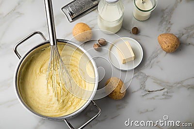 Ooking pot with mashed potatoes and ingredients as potato, milk, salt, butter, nutmeg with whisker and grinder on light marble Stock Photo