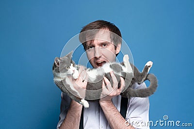 ooling around man holding cute gray and white cat on back and showing as if about going eat cat Stock Photo