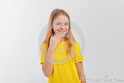 Portrait of embarrassed teen girl use hand cover mouth, stands in casual yellow t shirt over white studio background Stock Photo