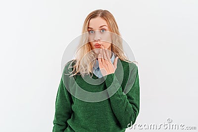 Oops. Portrait of young woman covering mouth, say as I made an error, omg gesture, looking insecure at camera, standing over white Stock Photo