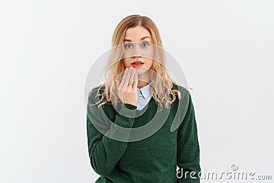 Oops. Portrait of young woman covering mouth, say as I made an error, omg gesture, looking insecure at camera, standing over white Stock Photo