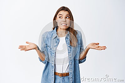 Oops sorry. Clueless young woman shrugging and looking away unsure, dont know and have no idea, nothing to tell Stock Photo