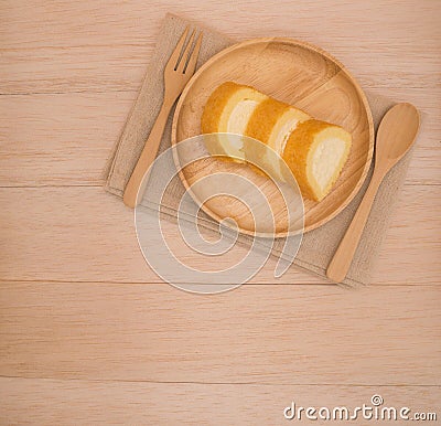 Op view vanilla cake roll on wooden dish with wooden spoon,fork on wooden background Stock Photo