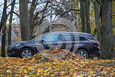 Opel Astra ST on the road with autumn leaves in the city park. Autumn landscape Editorial Stock Photo