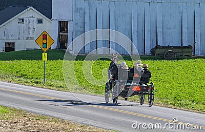 Open Amish Horse and Buggy With Family Riding in it Stock Photo