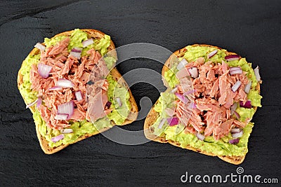 Open avocado sandwiches with tuna against dark slate Stock Photo