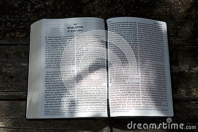 Open Bible in Revelation of Jesus Christ in chapters 1 and 2 with sunshine in the texts. Stock Photo