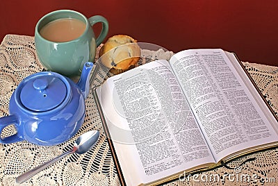 Open bible on table with vintage table cloth, teapot, mug and mu Stock Photo