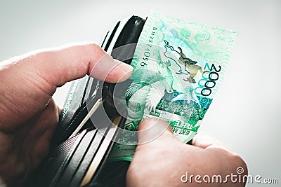 Open black wallet with tenge, Kazakhstan money in man`s hands close-up Stock Photo