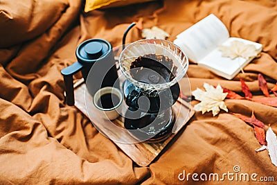 Open book and brewed coffee on a bed with autumn leaves in the morning, cosy home and calm concept Stock Photo