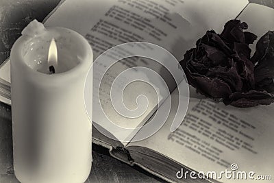 An open book with a candle. on the pages is a Bud of dried rose. Stock Photo