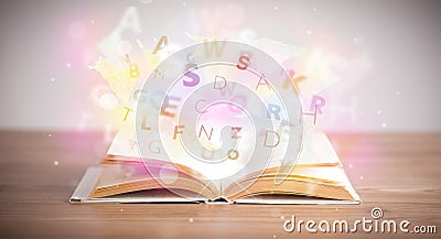 Open book with glowing letters on concrete background Stock Photo