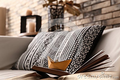 Open book with golden origami boat on comfortable sofa Stock Photo