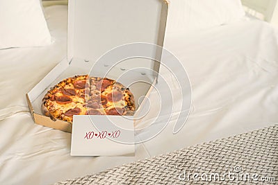 Open box of pizza on the big bed and card with Quote - xo xo xo. Valentine lettering love collection. Concept. Stock Photo