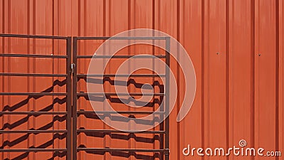 Open brown folding metal garage gate on orange corrugated steel wall Stock Photo