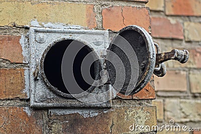 Open circular heating hood with black soot and gray iron cover on the brown brick wall Stock Photo