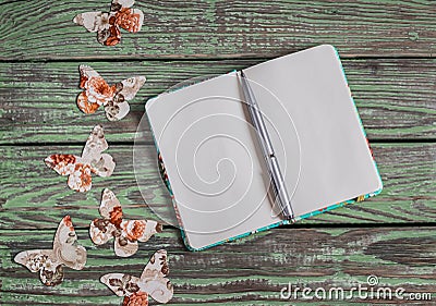 Open clean notepad and homemade paper butterfly on a wooden vintage background. Top view, free space for text. Stock Photo
