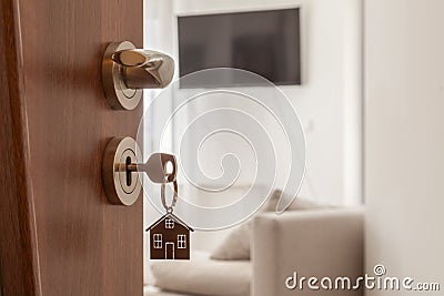 Open door to a new home. Door handle with key and home shaped keychain. Mortgage, investment, real estate, property and new home c Stock Photo