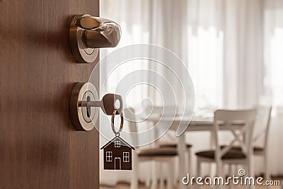 Open door to a new home. Door handle with key and home shaped keychain. Mortgage, investment, real estate, property and new home c Stock Photo