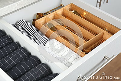 Open drawer with utensils and folded towels. Order in kitchen Stock Photo