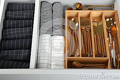 Open drawer with utensils and folded towels. Order in kitchen Stock Photo