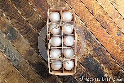 Open eco-friendly wooden box with eggs on diagonal wooden table. Stock Photo