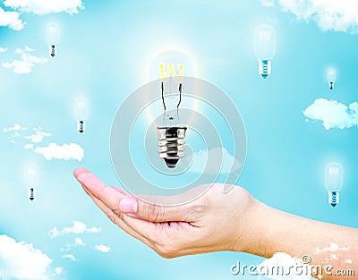 Open female hand with floating glowing lightbulb with blue sky a Stock Photo