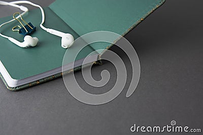 Open green page notebook with headphones and paper binder clips. Grey minimalistic background. Mock up, template for education or Stock Photo