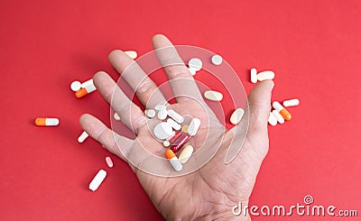 open hand on red background full of colored drugs and excessive consumption of antidepressants Stock Photo