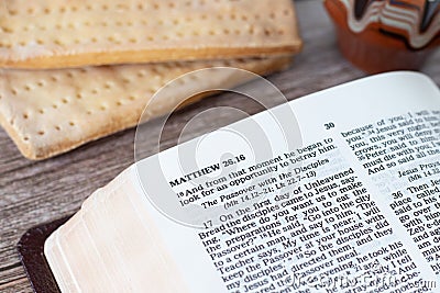 Open Holy Bible on the new testament Passover chapter with unleavened bread and a cup of wine on a wooden table Stock Photo