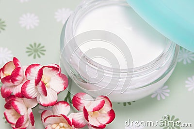 Open jar of cream with flowers Stock Photo