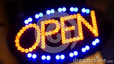 Open neon sign glowing in the dark. Vivid retro styled text at entrance on glass window. Colorful electric banner selective focus Stock Photo