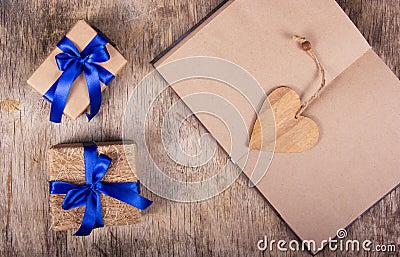 Open notebook with blank pages, valentine made of wood and boxes with gifts. Gift boxes with blue ribbon Stock Photo
