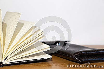 Open notebook and brown case on a wooden table Stock Photo