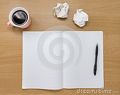 Open blank notebook, scrunched up paper and coffee cup on a wooden desk. Stock Photo