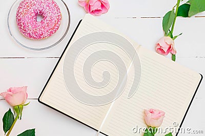 Open notebook with pastel pink roses and pink glazed donut Stock Photo